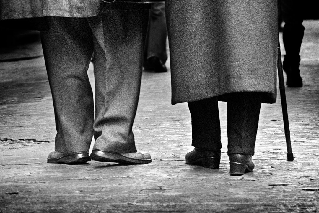 Two people standing, one with a walking stick.